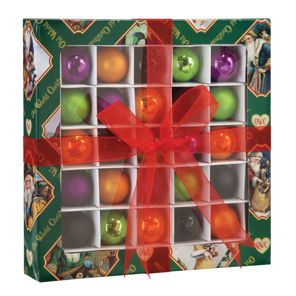 A festive gift box of colorful Christmas ornaments tied with a large red ribbon and bow. The green box features vintage-style holiday illustrations along the border.