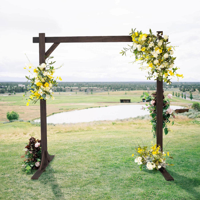 Wooden wedding arch adorned with floral arrangements overlooking a scenic landscape.