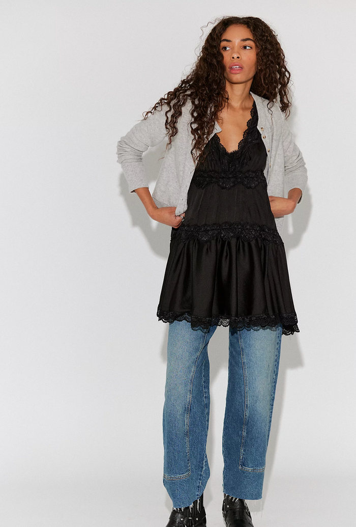 Woman wearing a black lace top and blue jeans against a white background