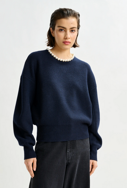Person wearing a navy blue sweater with a white background