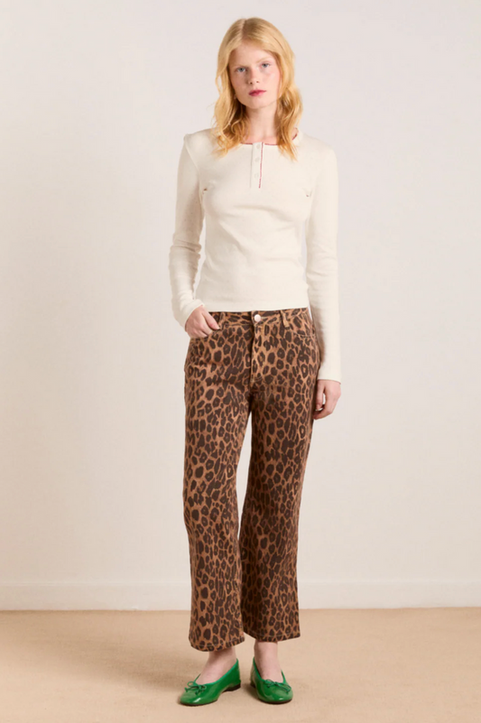 Woman wearing a cream top and leopard print pants against a white background