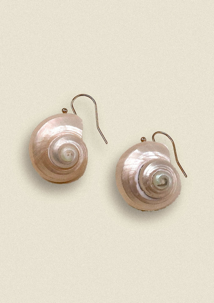 Shell-shaped earrings on a beige background