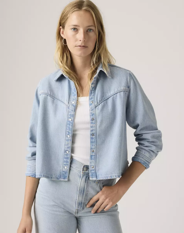 Woman wearing a light blue denim jacket with snaps.