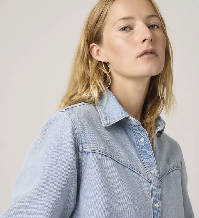Woman wearing a light blue denim jacket against a plain background