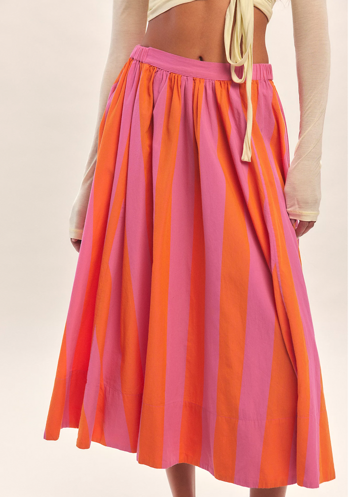 Person wearing a pink striped skirt on a plain background