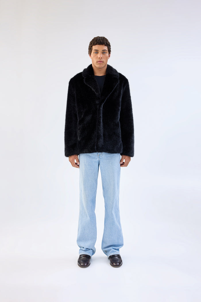Black faux fur jacket with notch lapel and cropped relaxed fit, worn over light-wash straight-leg jeans, front view