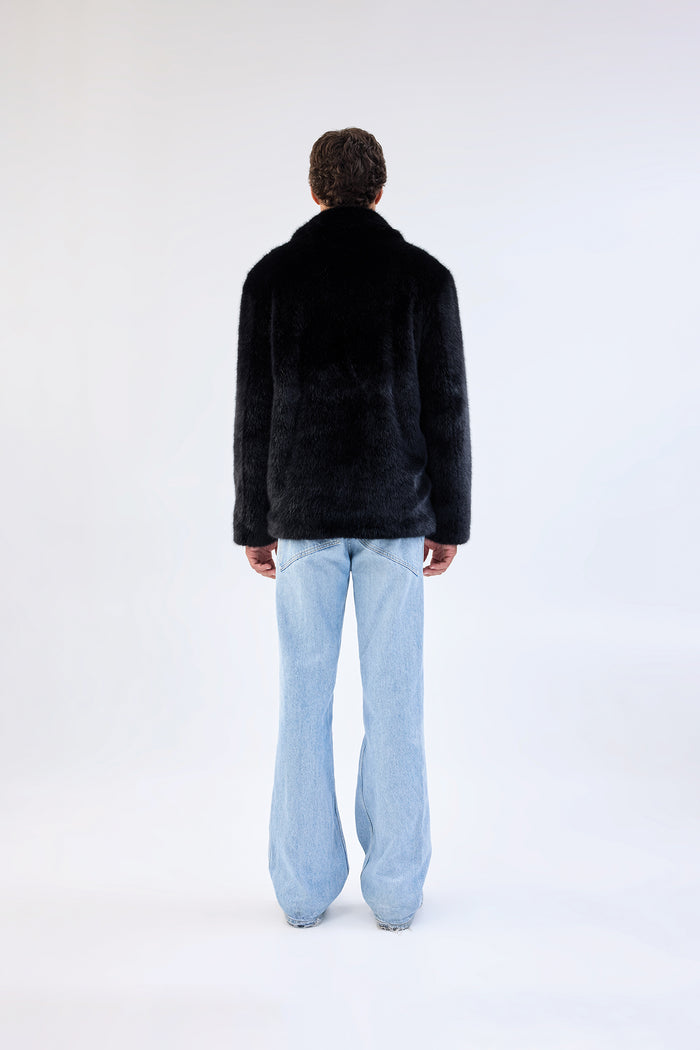Black faux fur jacket with notch lapel and cropped relaxed fit, worn over light-wash straight-leg jeans, back view