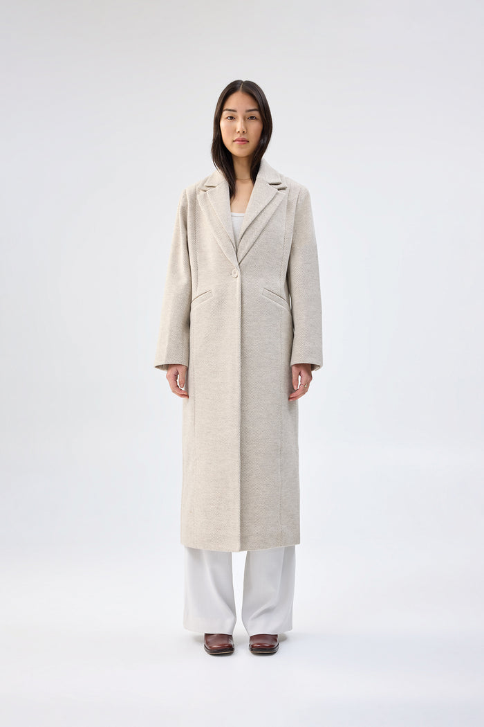 Beige textured faux wool coat with notch lapel, single-button closure, and full-length tailored fit, worn over white wide-leg trousers, front view