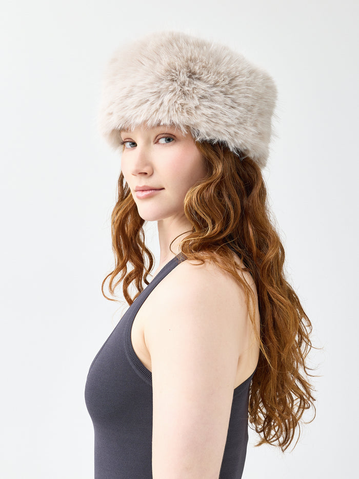 Woman wearing a beige faux fur hat on a white background