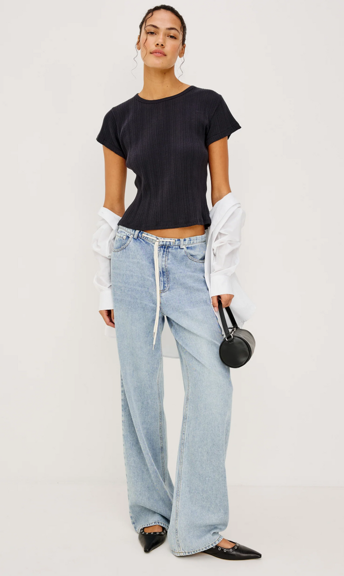 Person wearing a black t-shirt and light blue jeans on a white background