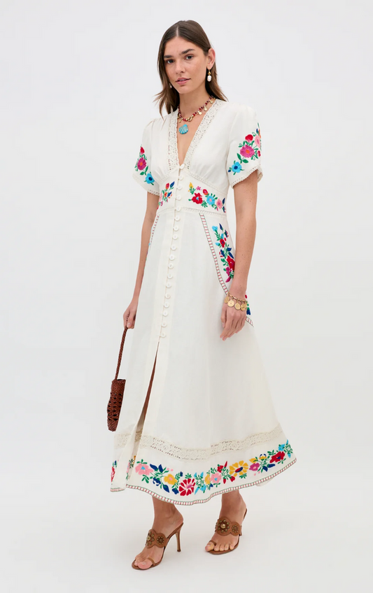 Woman wearing a white dress with floral embroidery on a white background