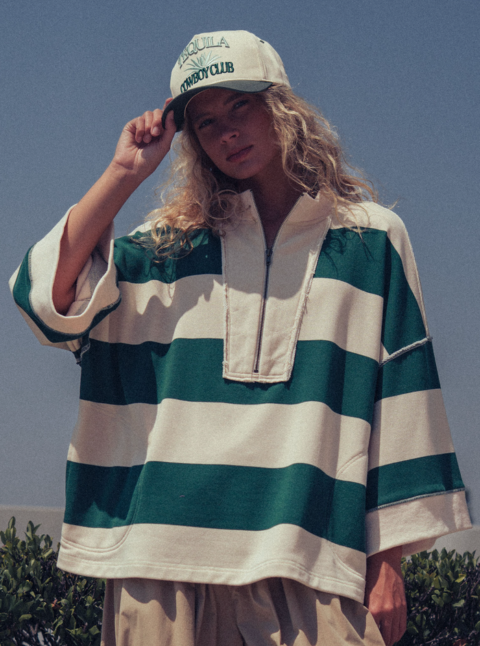 Person wearing a green and white striped shirt and cap outdoors