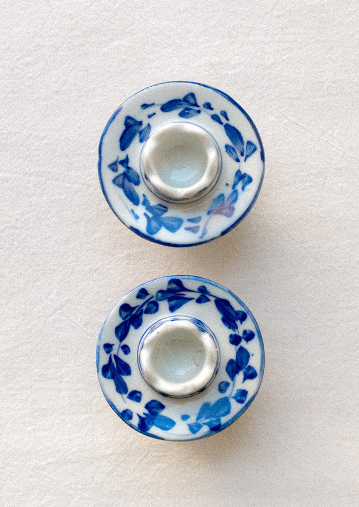 A pair of small blue and white floral print ceramic candleholders.