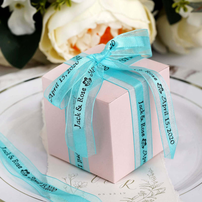 Pink gift box with blue ribbons and text for a wedding date.