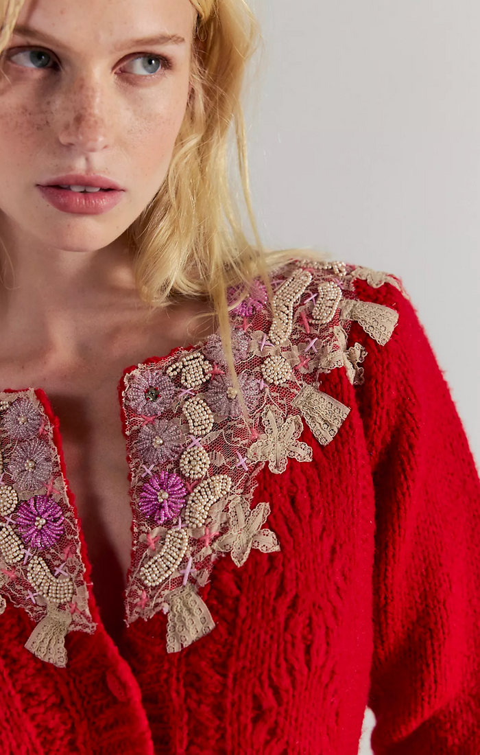 Red embroidered sweater worn by a model against a plain background