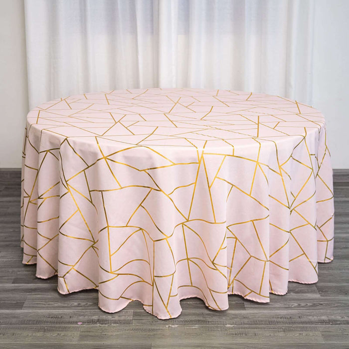 Round pink tablecloth with geometric gold pattern on a wooden surface.