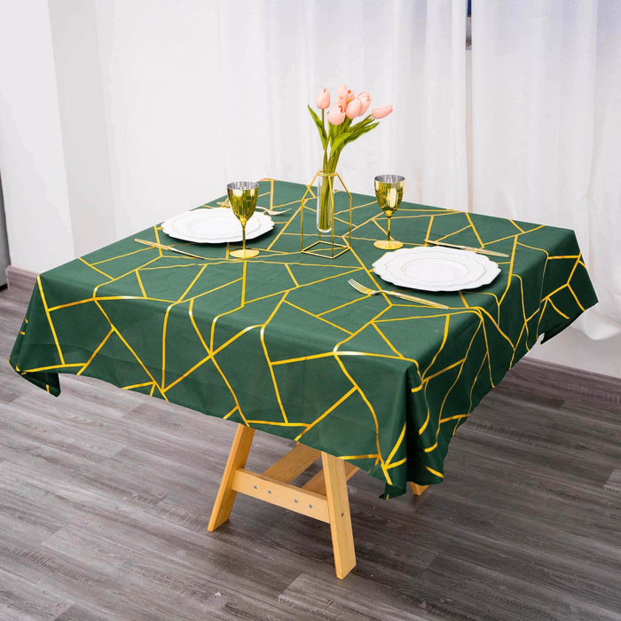 Green geometric tablecloth on a wooden table with floral centerpiece and dinnerware.