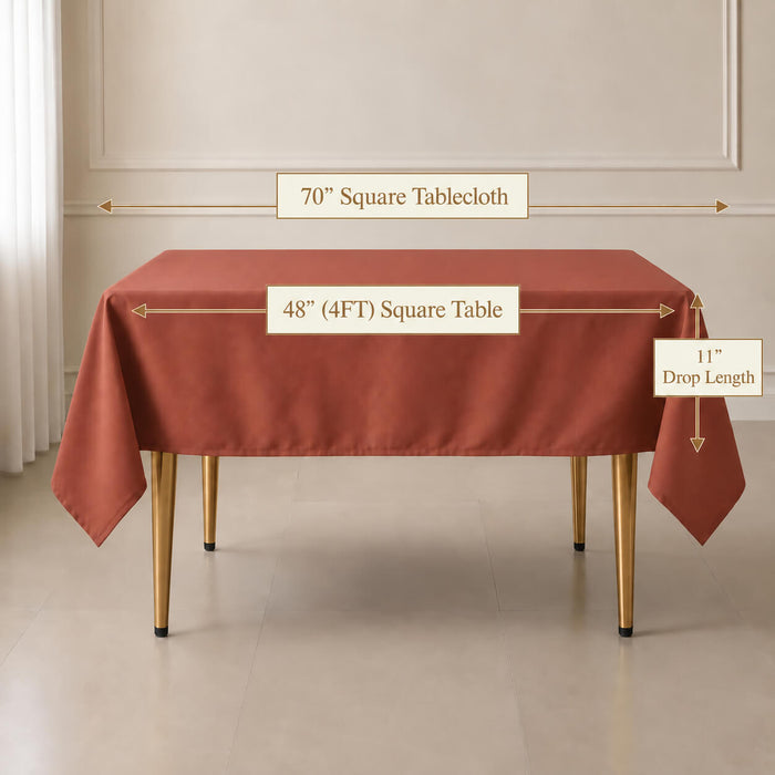 A square terracotta rust-red tablecloth draped over a rectangular table in a styled room setting, with measurement callouts indicating a 70" square tablecloth, 48" square table, and 11" drop length.