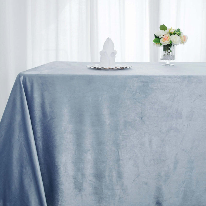 Elegant blue tablecloth on a dining table with floral centerpiece.