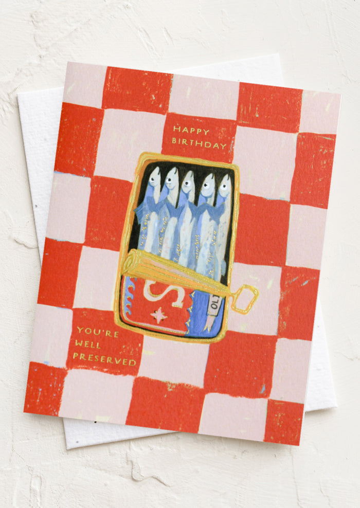 A red and pink checkered card with illustration of tin of sardines, texts reads "Happy Birthday, you're well preserved".