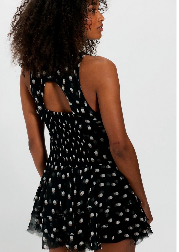 Woman wearing a black dress with white polka dots on a plain background