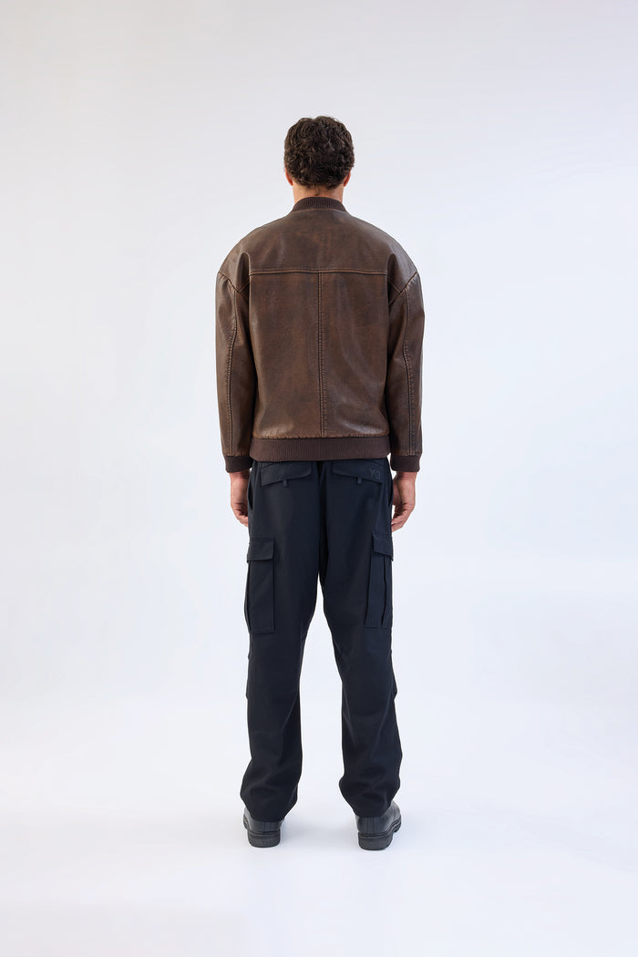 Brown vegan leather jacket with band collar and zip-front closure, cropped ribbed hem, worn over black cargo trousers, back view
