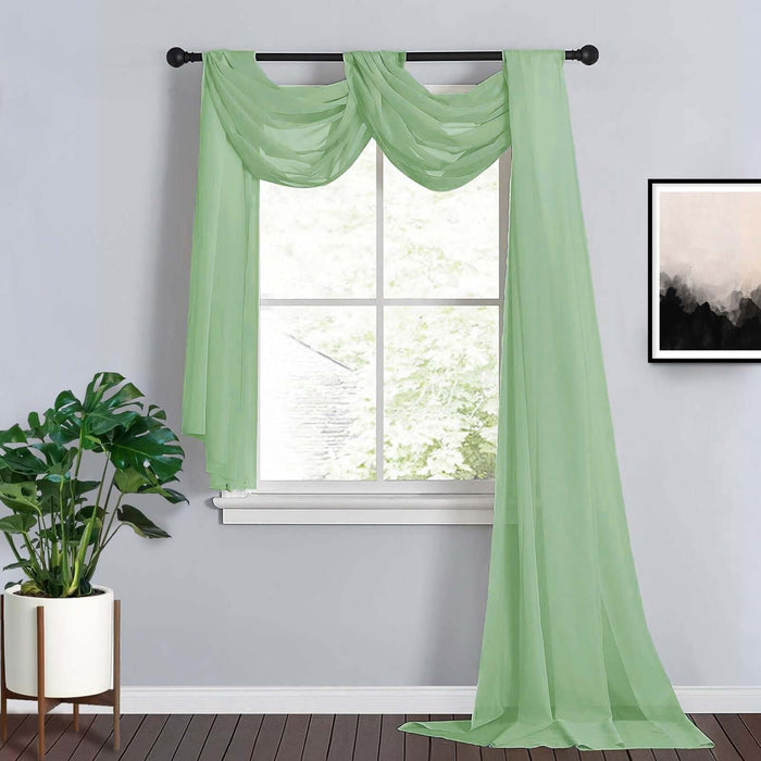 Sheer green curtain draped elegantly in a bright room with a plant and artwork.