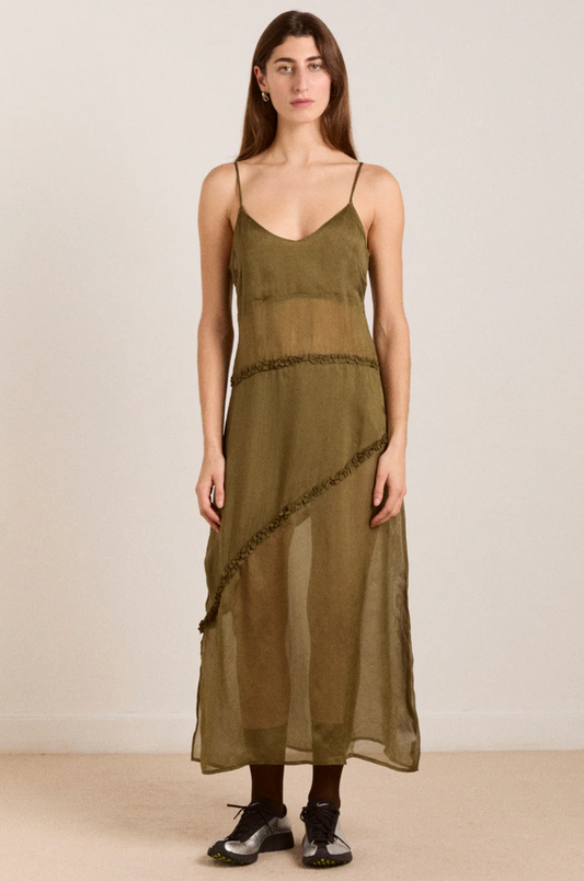 Woman wearing an olive green dress with a plain background