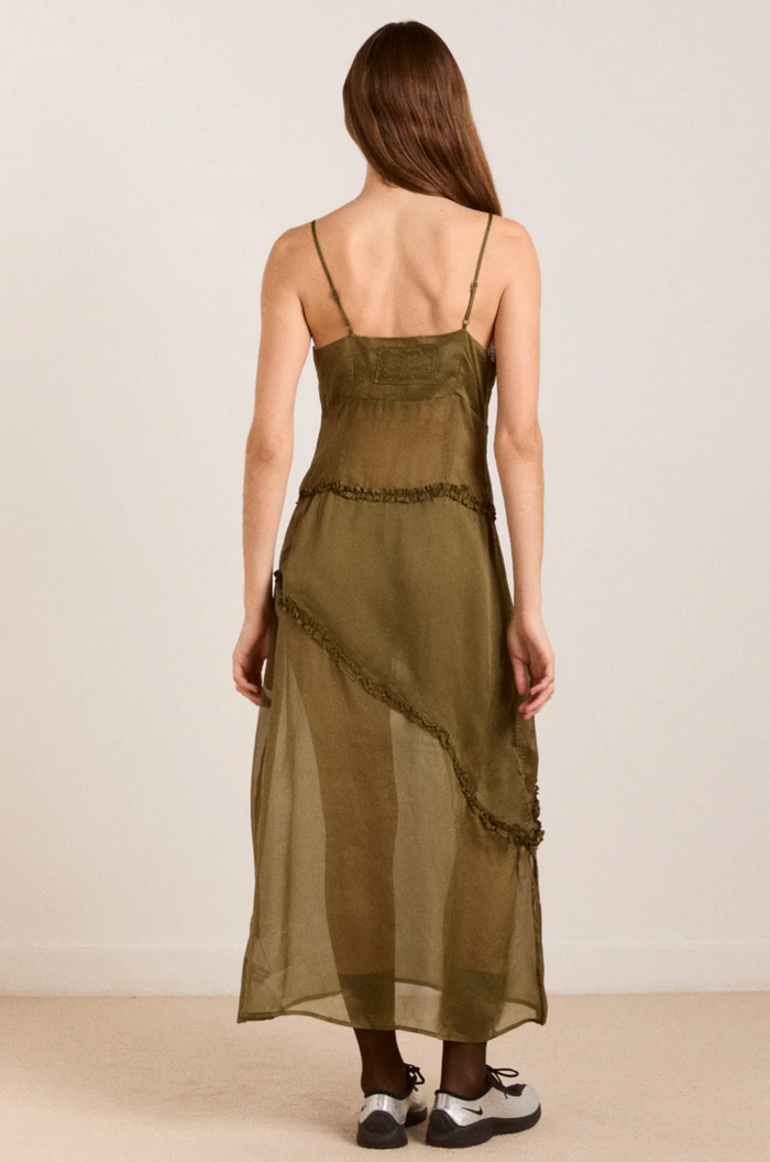 Woman wearing an olive green dress with a plain background