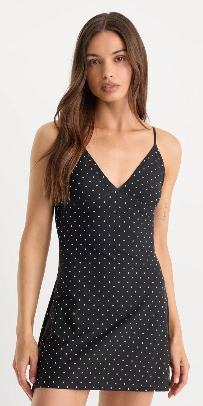 Woman wearing a black polka dot slip dress on a white background