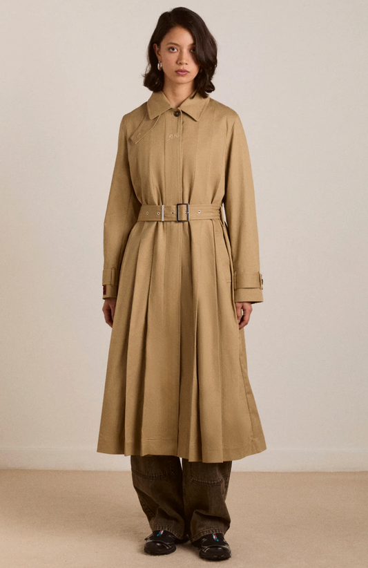 Woman wearing a beige trench coat on a plain background