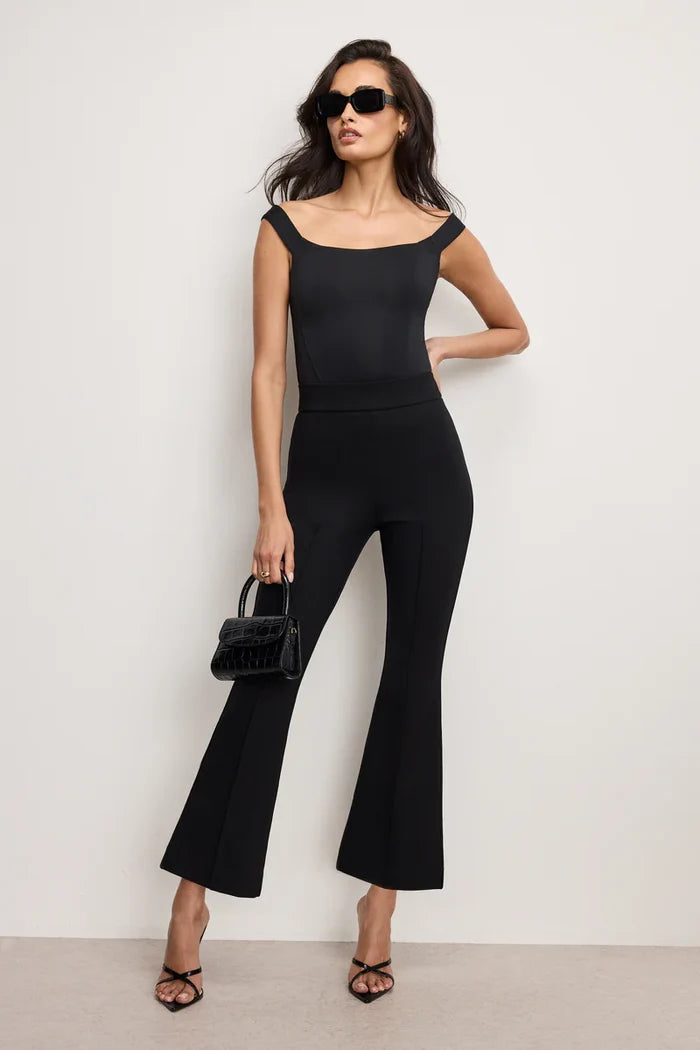 Woman wearing a black outfit with flared pants against a white background