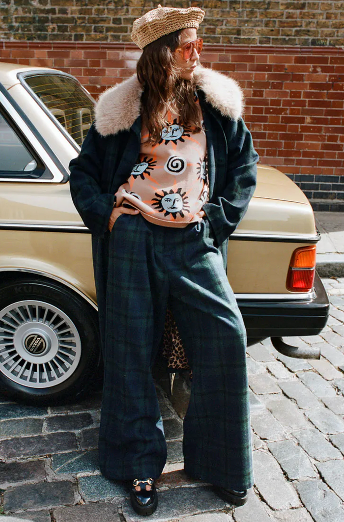 Person wearing a stylish outfit with a coat and sweater and matching plaid trouser pants.