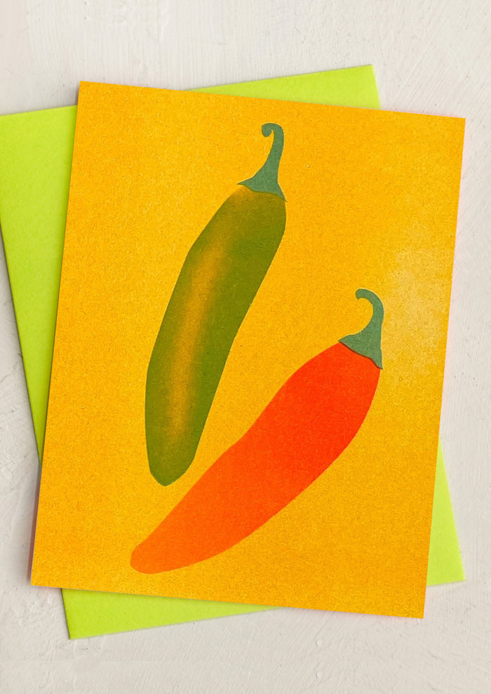 A risograph printed greeting card with red and green chiles on orange background.