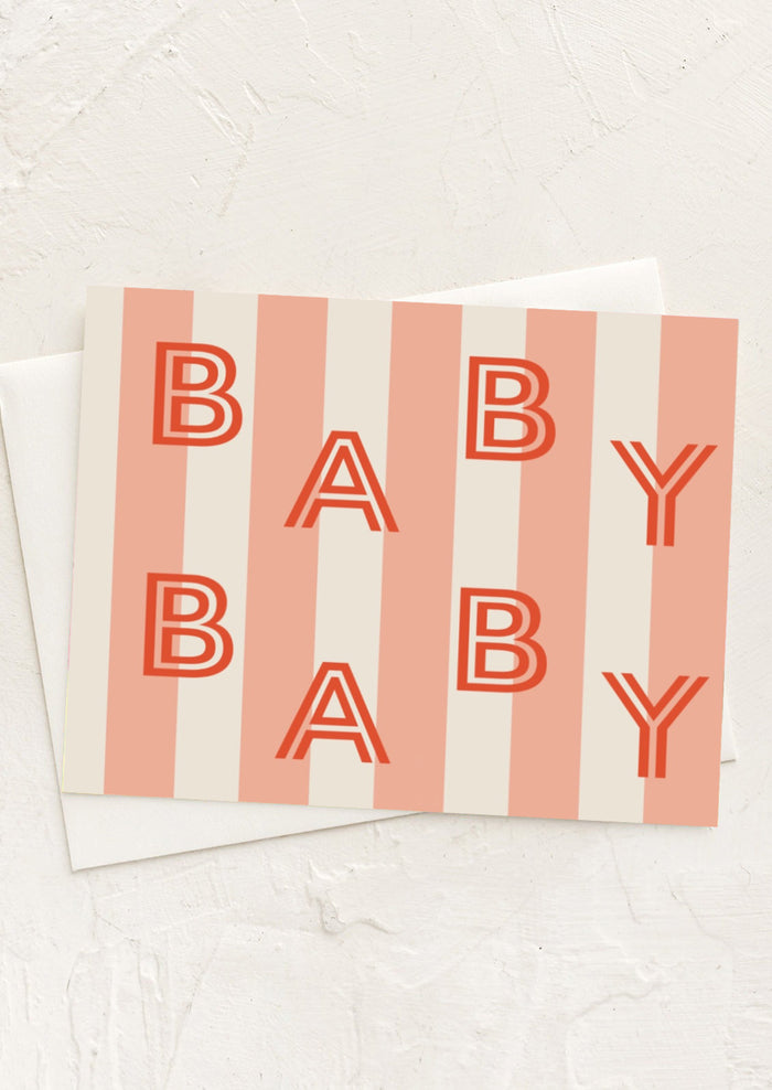 A greeting card with peach stripes reading "BABY BABY" in red letters.