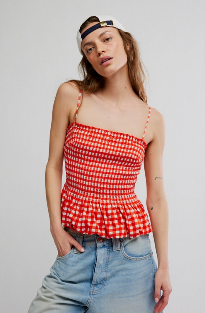 Woman wearing a red and white checkered top and blue jeans against a plain background