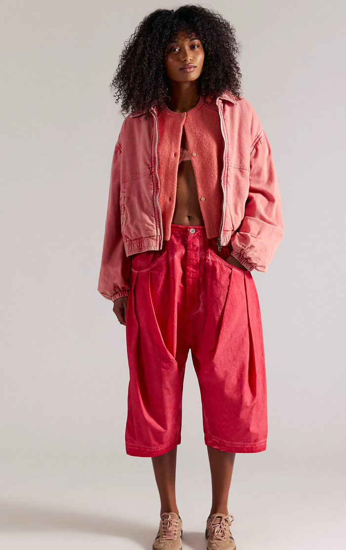 Person wearing a pink jacket and red pants against a plain background