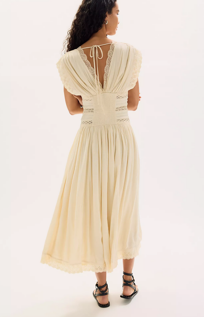 Woman wearing a beige dress with lace details on a white background