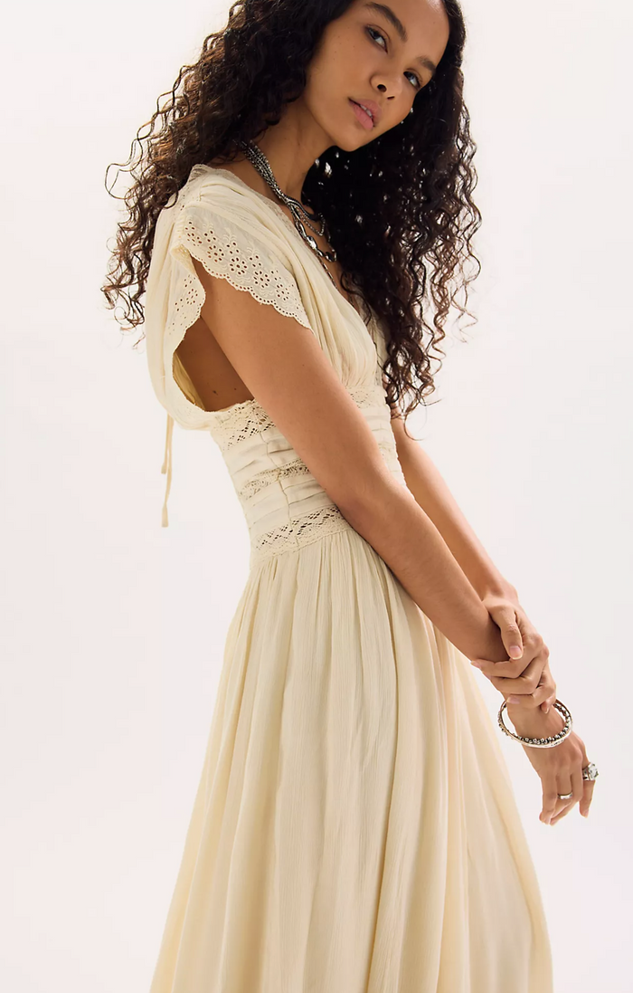 Woman wearing a beige dress with lace details on a white background