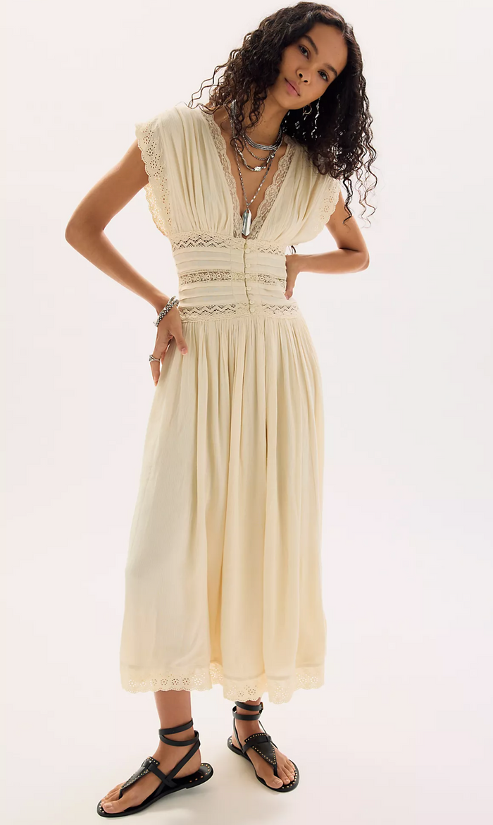 Woman wearing a beige dress with intricate details on a white background