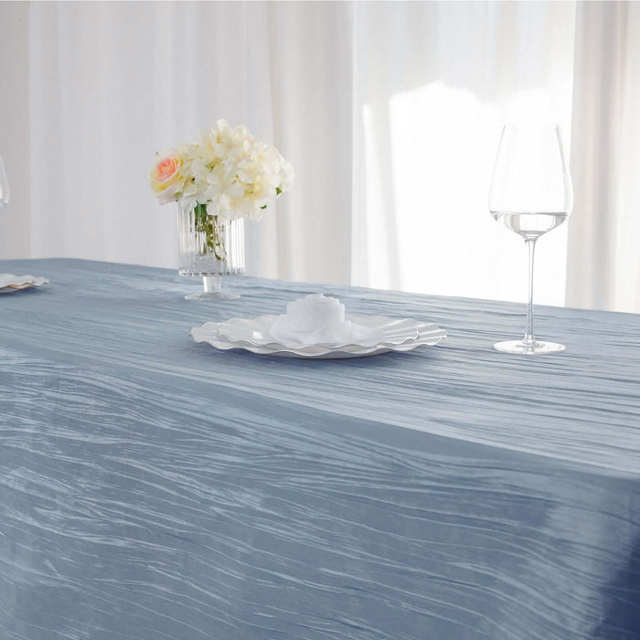 Elegant blue tablecloth set with decorative plates and wine glasses on a table.
