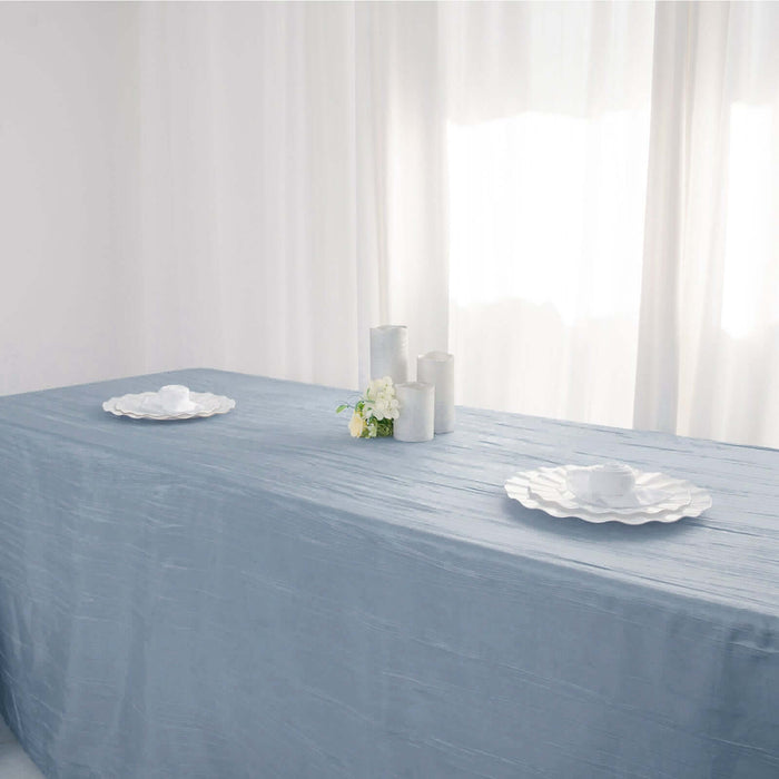 Elegant blue tablecloth with white plates and candles on a dining table.