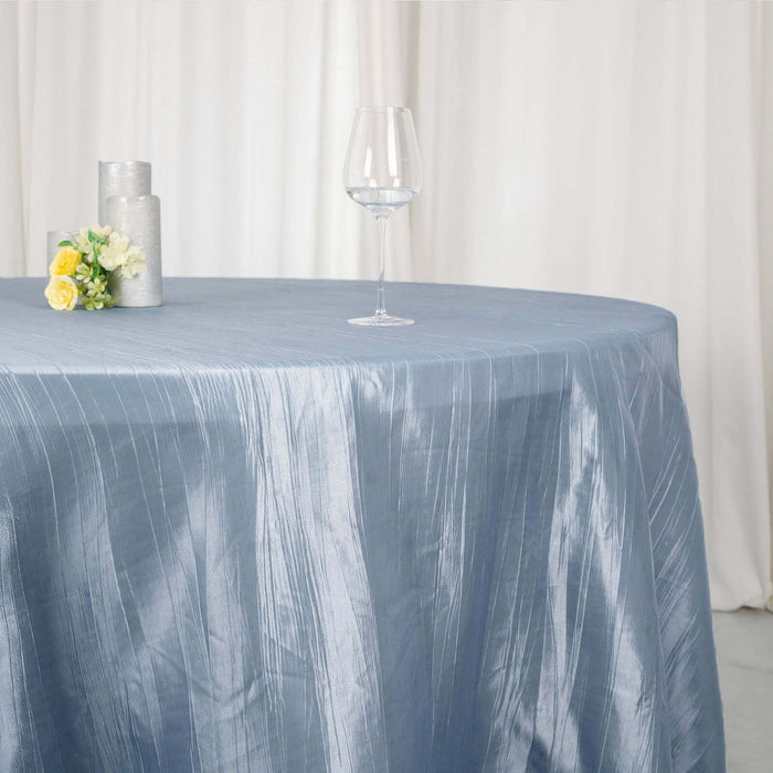 Elegant blue tablecloth draped on a round table with glassware and floral decor.