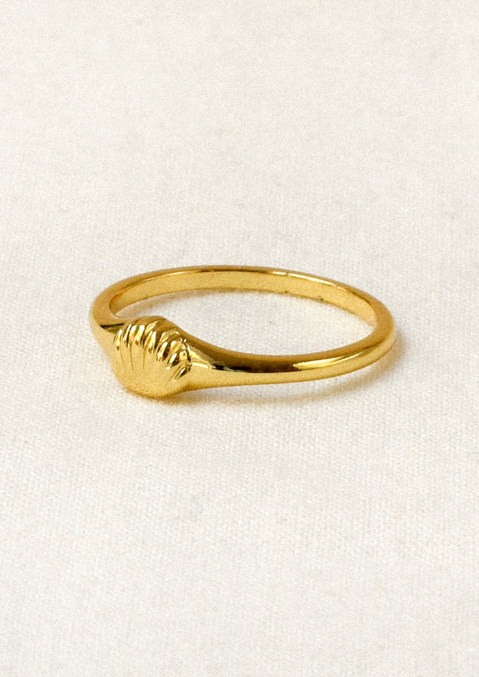 A gold ring with a tiny gold seashell on the front.
