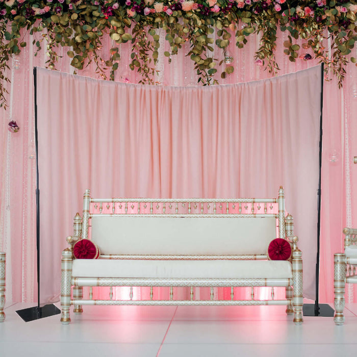 Elegant white sofa with decorative accents against a pink backdrop.