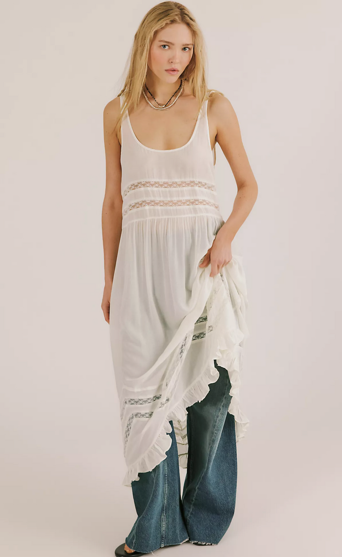 Woman wearing a white sleeveless top and blue jeans with a sheer white fabric.
