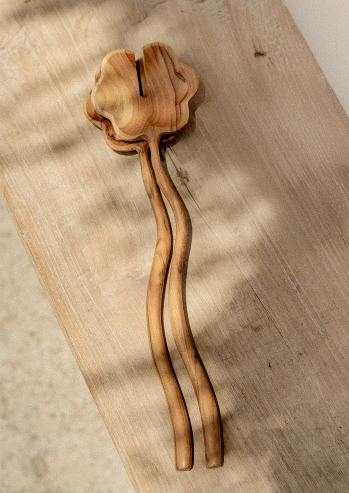 A pair of salad servers with flower shaped spoon and wavy handle.