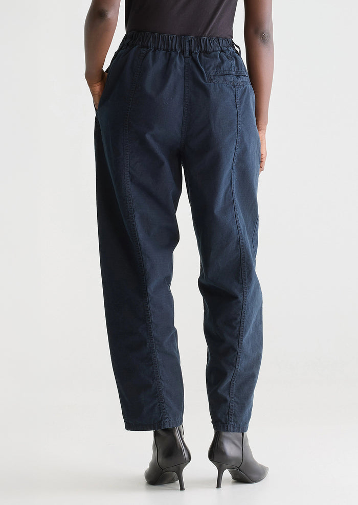 A woman wearing a pair of navy blue pants with tapered leg, in ripstop cotton fabric.