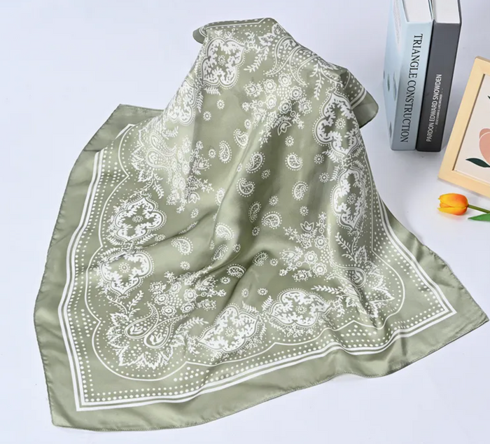 Green scarf with white paisley pattern on a light gray background